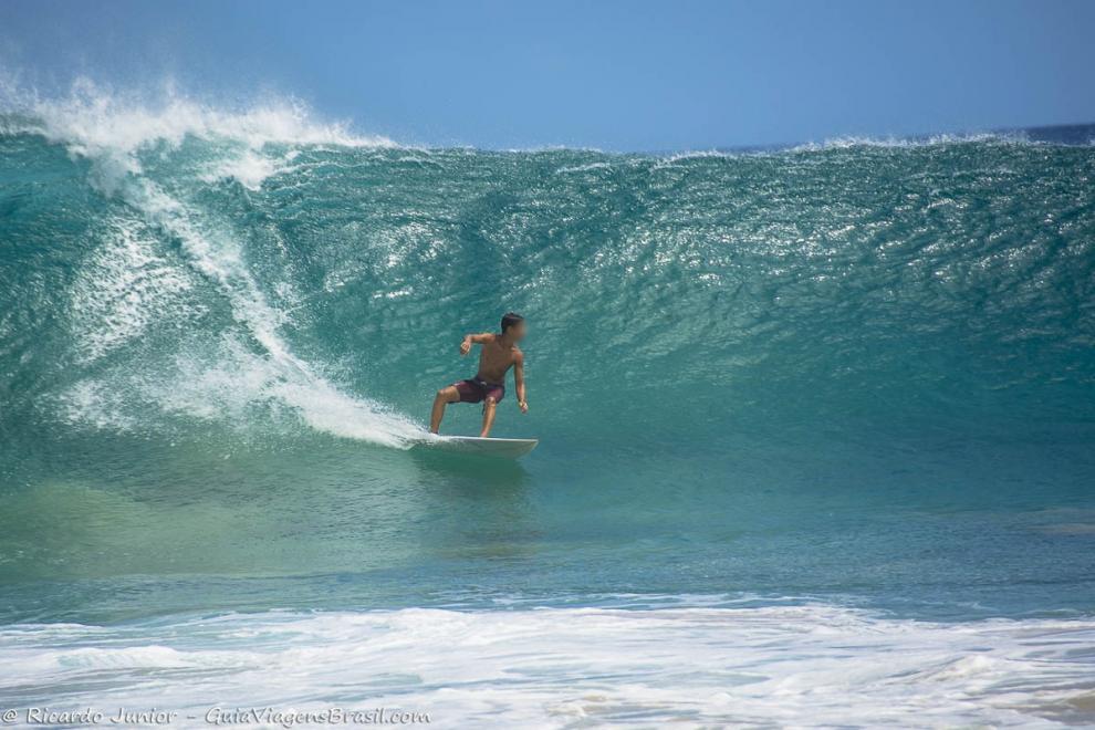 Imagem de um menino surfando em Fernando de Noronha.